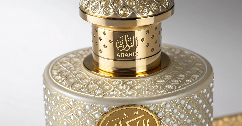 A detailed macro shot of a perfume bottle cap and shoulder, showcasing a multi-process decoration, like a frosted finish with a gold hot-stamped logo.