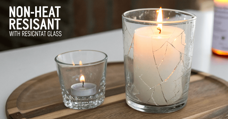 A cracked drinking glass with a warning sign over it, illustrating why an untested glass container is unsafe for candles.