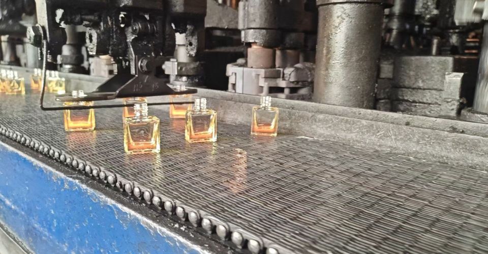 The clean and modern production line at LOM GLASSWORKS, showing empty glass nail polish bottles moving along a conveyor belt.