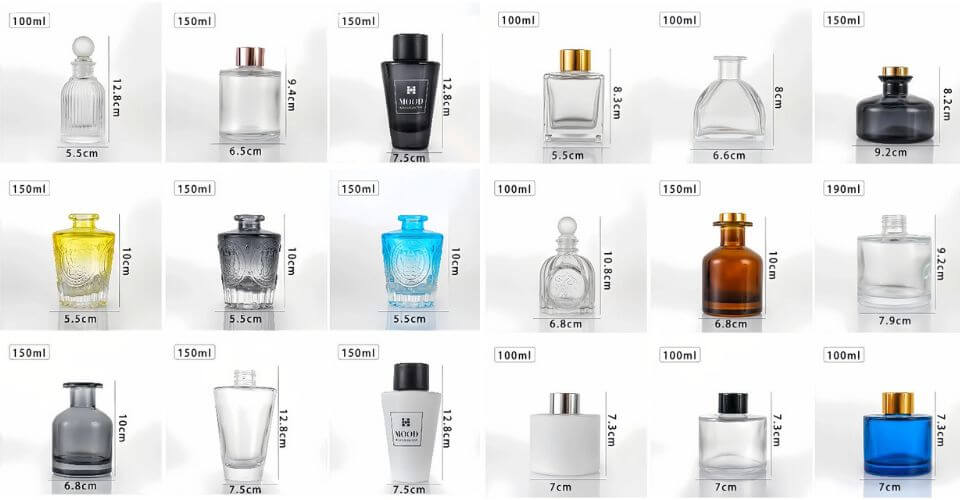 A professional product photograph showcasing a variety of elegant wholesale glass diffuser bottles from LOM GLASSWORKS, featuring different shapes, volumes, and clear, high-quality glass.