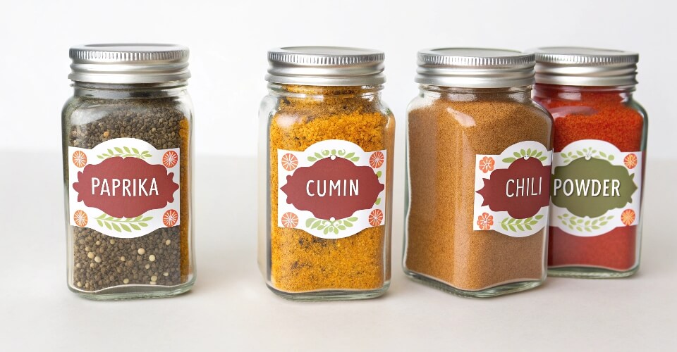 A neat row of 4 oz Mason jars filled with colorful spices and labeled clearly.
